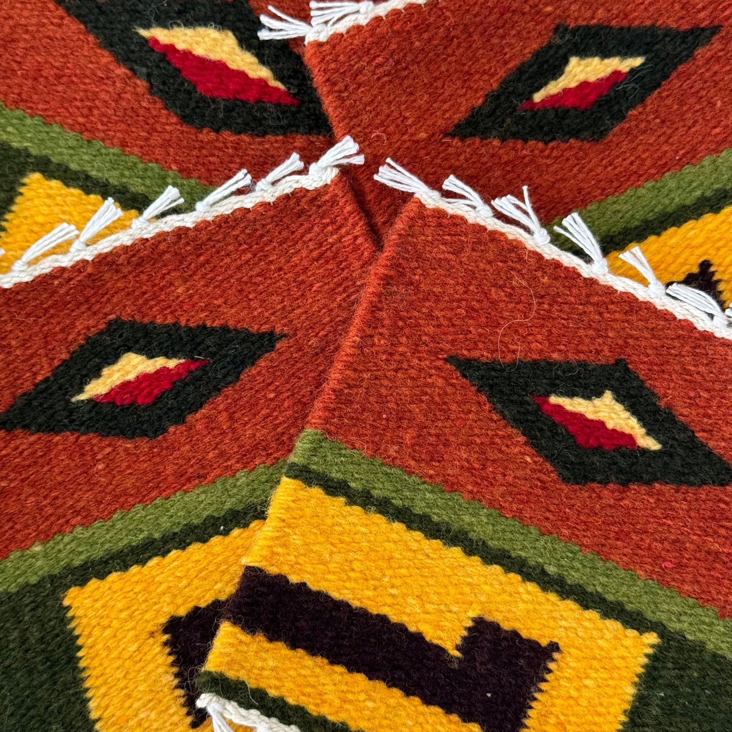 close up of handwoven wool coasters with geometric patterns, crafted using natural Peruvian dyes.